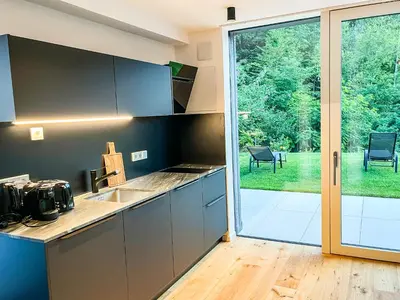 a kitchen with a large glass door leading to a yard at Garden Apartment Untermühle in Bressanone