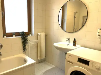 a bathroom with a sink and a washing machine at Kurhaus Apartment + parking in Merano