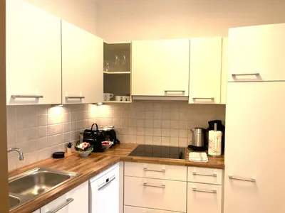 a kitchen with white cabinets and a sink at Kurhaus Apartment + parking in Merano