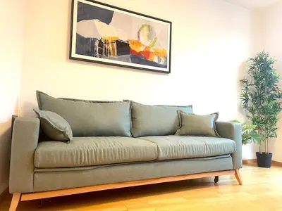 a couch in a living room with a picture on the wall at Kurhaus Apartment + parking in Merano