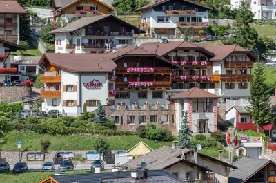a restaurant with wooden tables and white chairs at Hotel Carmen Dolomites in Santa Cristina in Val Gardena