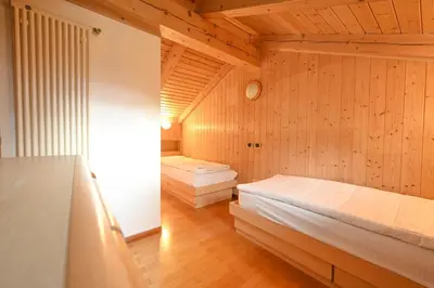 a bedroom with two beds in a room with wooden walls at Majon Fior de Bosch 2 in Campitello di Fassa