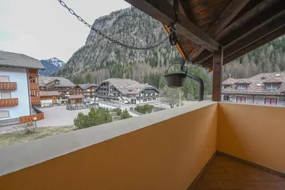 a balcony with a view of a town and mountains at Majon Fior de Bosch 2 in Campitello di Fassa