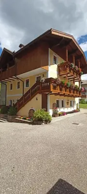 a large building with a balcony and flowers on it at Majon Fior de Bosch 2 in Campitello di Fassa