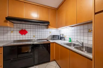 a kitchen with wooden cabinets and a stainless steel sink at Majon Fior de Bosch 2 in Campitello di Fassa