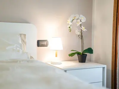 a white bed with a table with a plant on it at Apartment Condominio Giulia by Interhome in Alba di Canazei