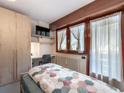 a bedroom with a bed and a desk and windows at Apartment Condominio Giulia by Interhome in Alba di Canazei