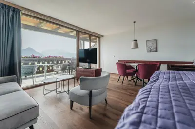 a bedroom with a bed and a living room with a view at Apartments by Bemelmans-Post in Collalbo