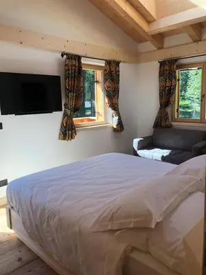 a bedroom with a bed and a flat screen tv at Rifugio Lago D'Ajal in Col