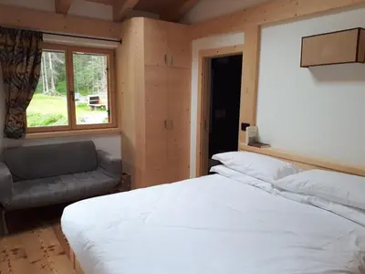 a bedroom with a large white bed and a window at Rifugio Lago D'Ajal in Col