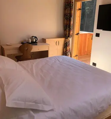a bedroom with a white bed and a sliding door at Rifugio Lago D'Ajal in Col