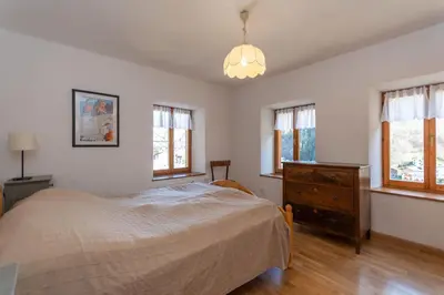 a bedroom with a bed and a dresser and windows at Casa Narciso in Rocca Pietore