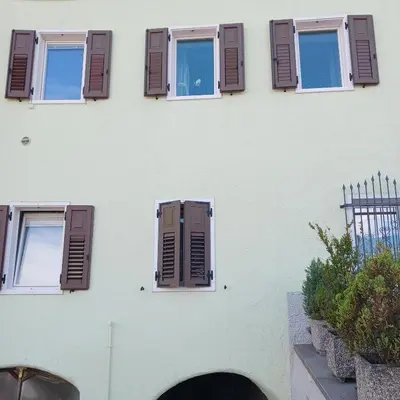 a white building with brown shutters on it at Rosa e Margherita in Brez