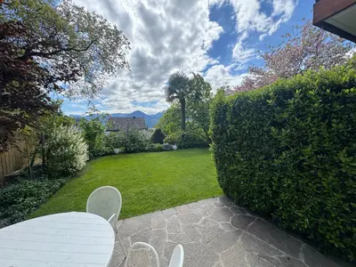 a garden with a white table and chairs next to a hedge at Appartements Lena in Merano