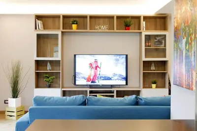 a living room with a blue couch and a tv at CASA YARA - 3 camere, 2 bagni, parcheggio Dolomiti Affitti in Cavalese