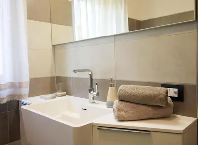 a bathroom with a sink and a mirror at CASA YARA - 3 camere, 2 bagni, parcheggio Dolomiti Affitti in Cavalese
