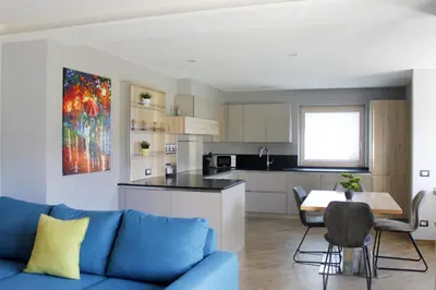 a living room with a blue couch and a kitchen at CASA YARA - 3 camere, 2 bagni, parcheggio Dolomiti Affitti in Cavalese