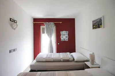 a bedroom with a bed and a red wall at CASA YARA - 3 camere, 2 bagni, parcheggio Dolomiti Affitti in Cavalese