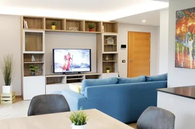 a living room with a blue couch and a tv at CASA YARA - 3 camere, 2 bagni, parcheggio Dolomiti Affitti in Cavalese