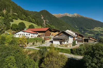 a group of buildings in a valley with mountains at Pfitscherhof in Campo di Trens