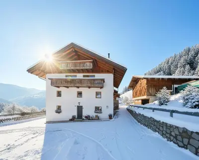 a house with a wooden roof in the snow at Pfitscherhof in Campo di Trens