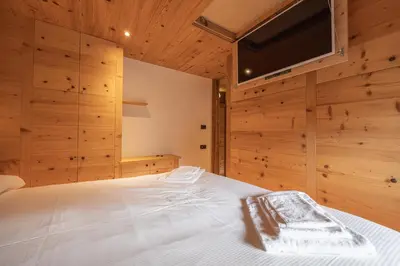 a bedroom with a white bed with wooden walls at Casa Ca dei Pini in Cortina dʼAmpezzo