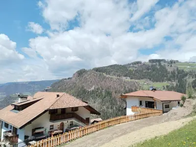 a house on a hill with mountains in the background at Waldnerhof in Soprabolzano