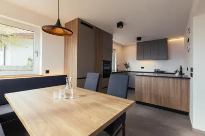 a kitchen and dining room with a wooden table at Alpenglow Apartments in Collalbo