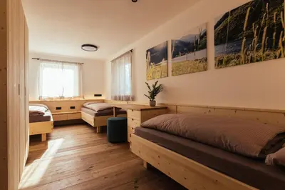 a bedroom with two beds and a desk at Alpenglow Apartments in Collalbo