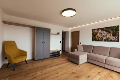 a living room with a couch and a chair at Alpenglow Apartments in Collalbo